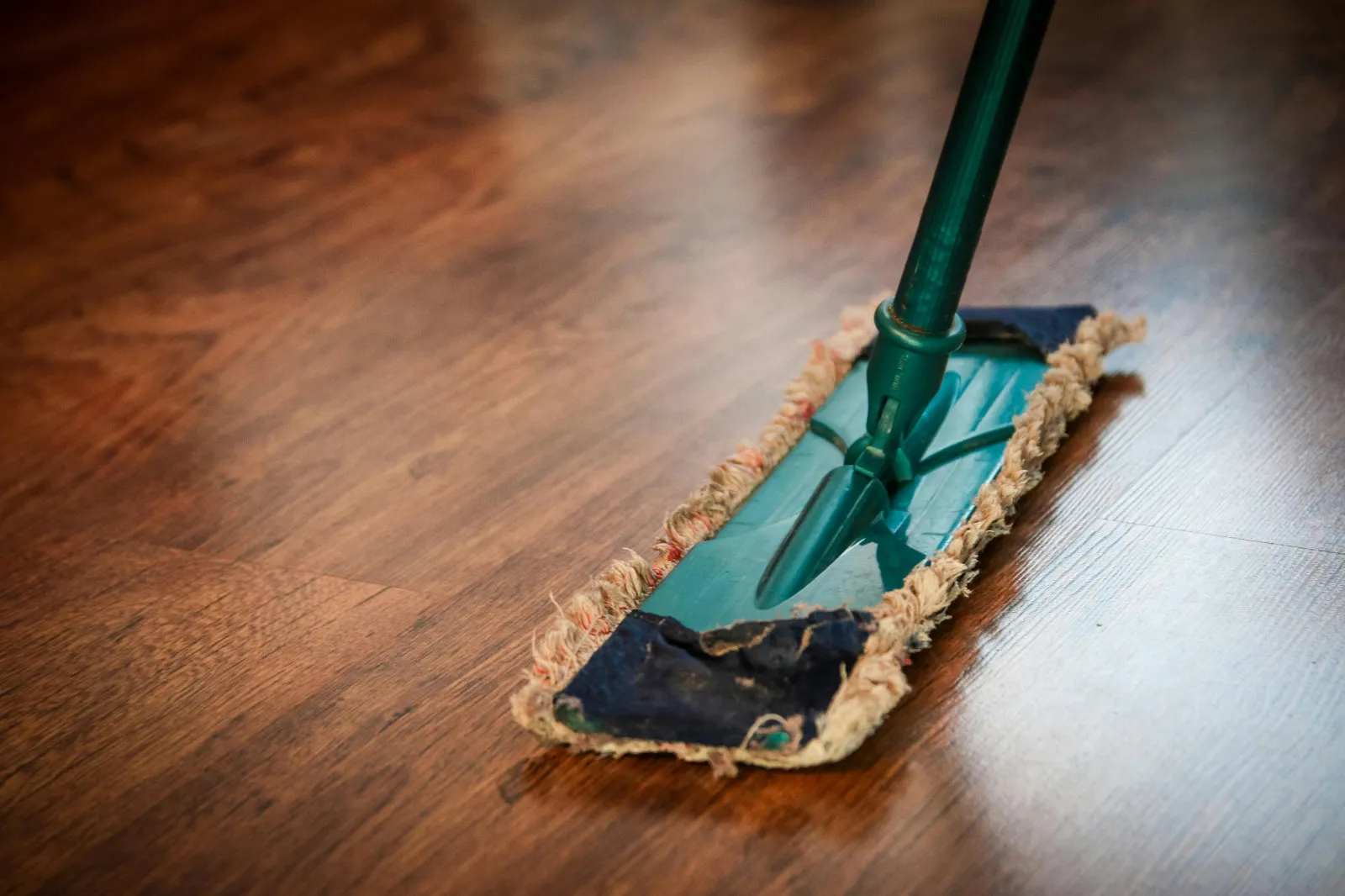 Flat microfiber mop cleaning a glossy herringbone hardwood floor