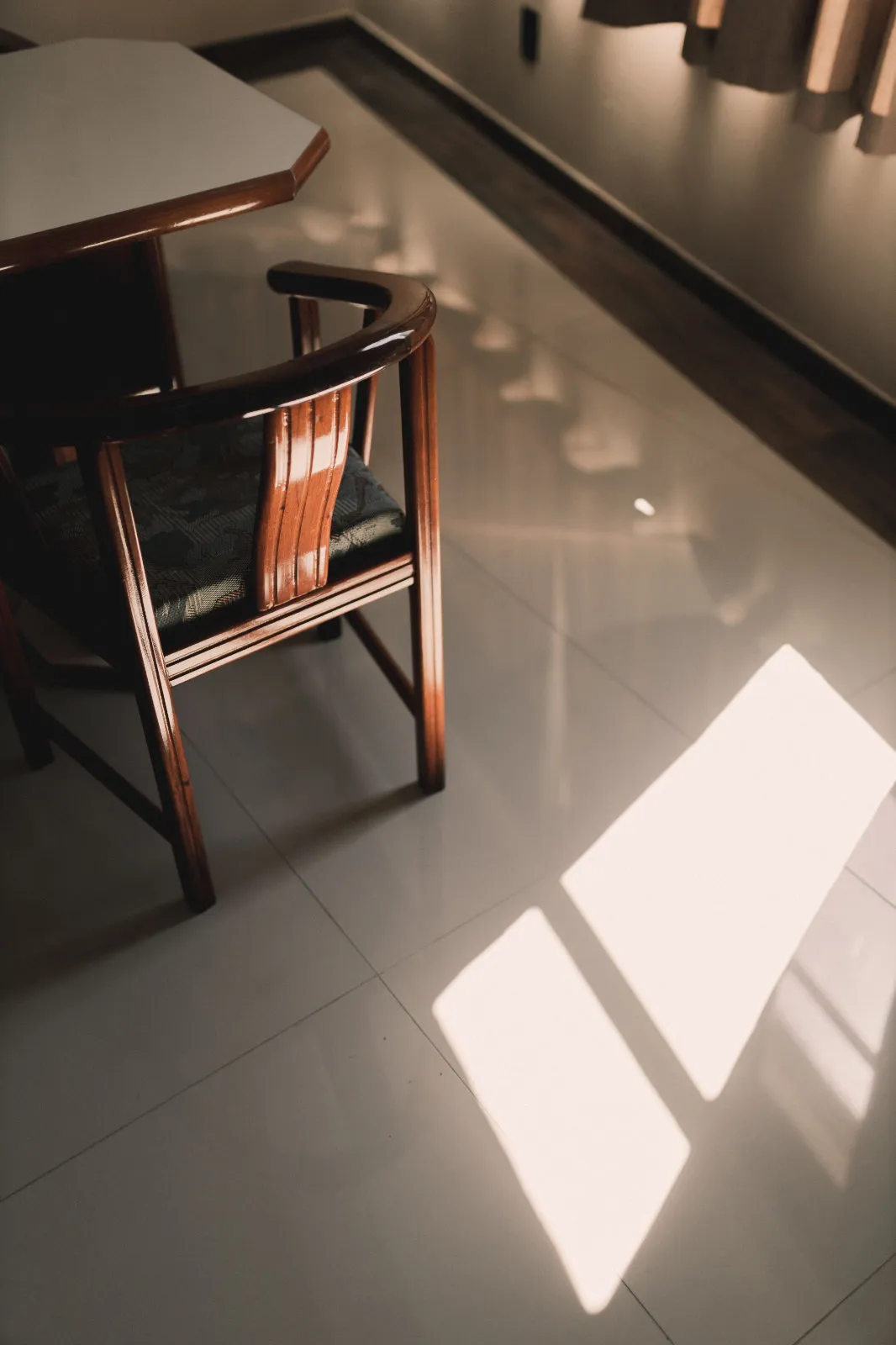 Large-format polished light porcelain tile flooring in a sunlit kitchen reflecting natural light